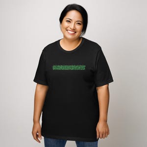 Puede incluir: Una camiseta negra con un gr&aacute;fico verde de un patr&oacute;n de c&oacute;digo binario.