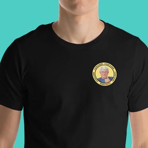 May include: Black t-shirt with a yellow circle graphic featuring a man with a thumbs up and the text "Clean Coder" repeated around the circle.