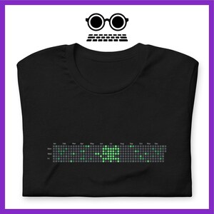 Peut inclure: T-shirt noir avec un motif de calendrier pixelis&eacute; vert. Le calendrier affiche les jours de la semaine et les mois de l'ann&eacute;e.