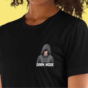 May include: Black t-shirt with a graphic of a person in a hooded sweatshirt. The text "DARK MODE" is below the graphic.