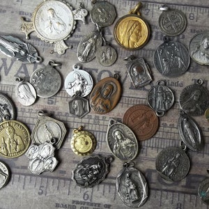 K&ouml;nnte beinhalten: Eine Sammlung antiker religi&ouml;ser Medaillen in verschiedenen Formen und Gr&ouml;&szlig;en. Die Medaillen sind aus Silber, Bronze und Goldt&ouml;nen gefertigt und zeigen religi&ouml;se Figuren und Symbole. Einige Medaillen haben aufwendige Details und sind auf einem Vintage-Hintergrund angeordnet.