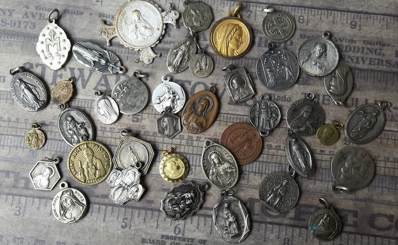 K&ouml;nnte beinhalten: Eine Sammlung antiker religi&ouml;ser Medaillen in verschiedenen Formen und Gr&ouml;&szlig;en. Die Medaillen sind aus Silber, Bronze und Goldt&ouml;nen gefertigt und zeigen religi&ouml;se Figuren und Symbole. Einige Medaillen haben aufwendige Details und sind auf einem Vintage-Hintergrund angeordnet.