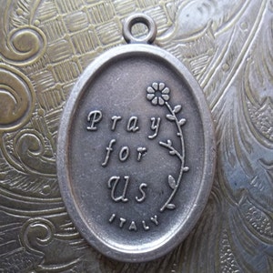 Peut inclure: Breloque en argent grav&eacute; des mots "Priez pour nous" et "Italie". Un petit motif de fleur est &eacute;galement grav&eacute; sur le breloque.