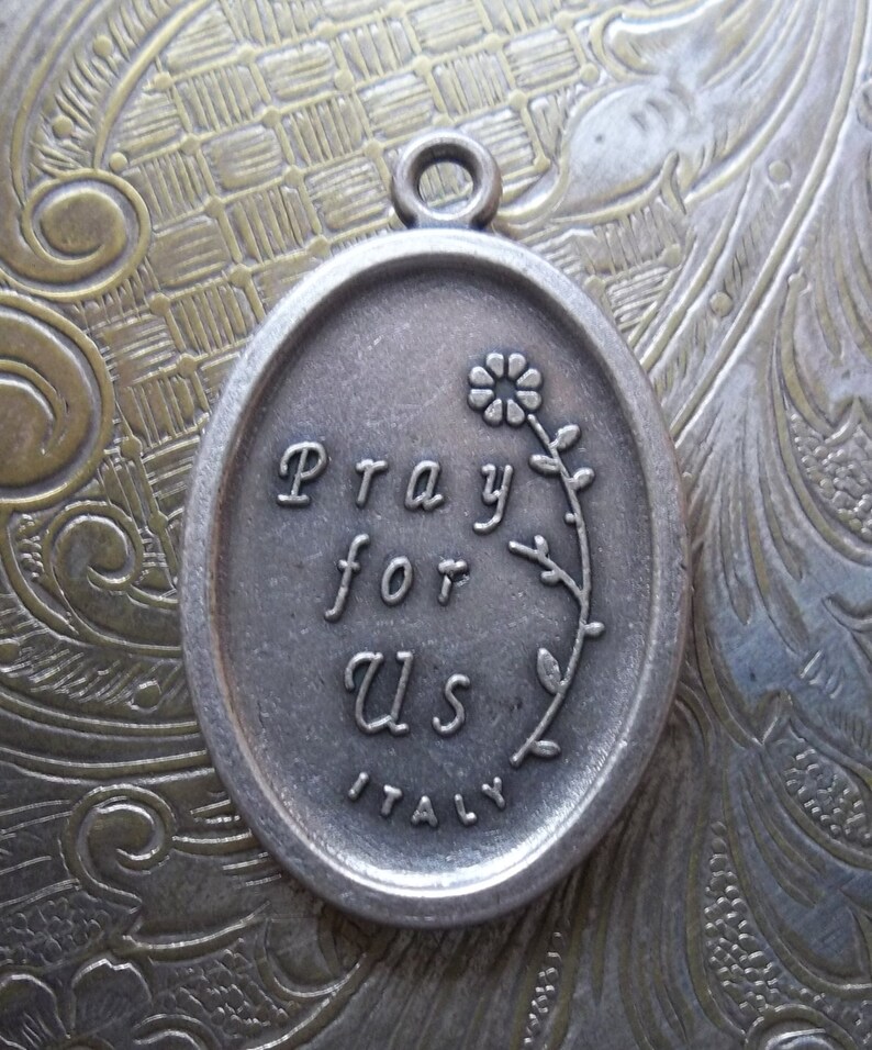 Peut inclure: Breloque en argent grav&eacute; des mots "Priez pour nous" et "Italie". Un petit motif de fleur est &eacute;galement grav&eacute; sur le breloque.