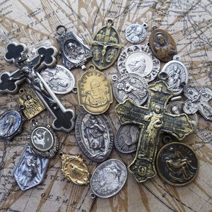 May include: A collection of vintage religious medallions and crosses, featuring various saints and religious figures. The medallions are made of silver and gold-toned metal and have intricate designs. The crosses are made of black and silver metal and have a worn, antique look.