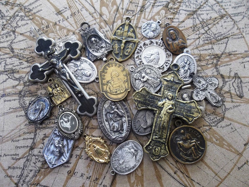 May include: A collection of vintage religious medallions and crosses, featuring various saints and religious figures. The medallions are made of silver and gold-toned metal and have intricate designs. The crosses are made of black and silver metal and have a worn, antique look.