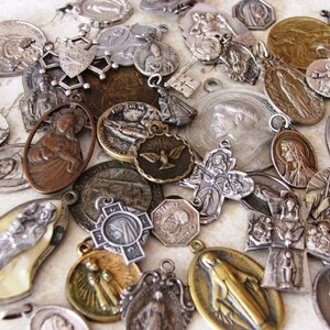 Pu&ograve; includere: Una collezione di ciondoli e ciondoli religiosi antichi. I ciondoli sono in argento e bronzo, raffiguranti figure religiose, croci e altri simboli. Alcuni presentano dettagli intricati e mostrano diversi segni di usura.