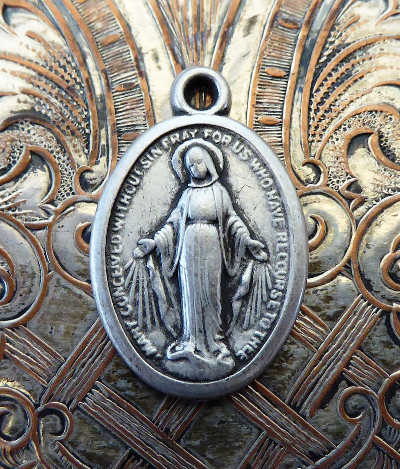 May include: Silver oval pendant with a depiction of the Virgin Mary and the text "Pray for us who have recourse to thee without sin".