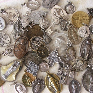 K&ouml;nnte beinhalten: Eine Sammlung antiker religi&ouml;ser Anh&auml;nger und Charms in verschiedenen Formen und Gr&ouml;&szlig;en. Die Anh&auml;nger sind aus Silber und Bronze gefertigt und zeigen religi&ouml;se Figuren und Symbole. Einige haben aufwendige Details und sind abgenutzt.