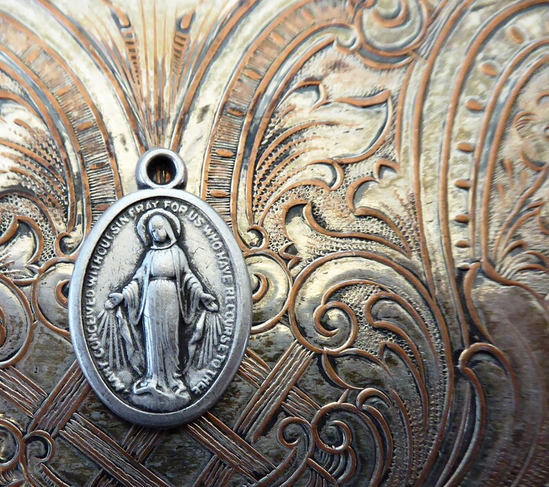 May include: Silver oval pendant with a depiction of the Virgin Mary and the text "CONCEIVED WITHOUT SIN, PRAY FOR US WHO HAVE RECOURSE TO THEE".