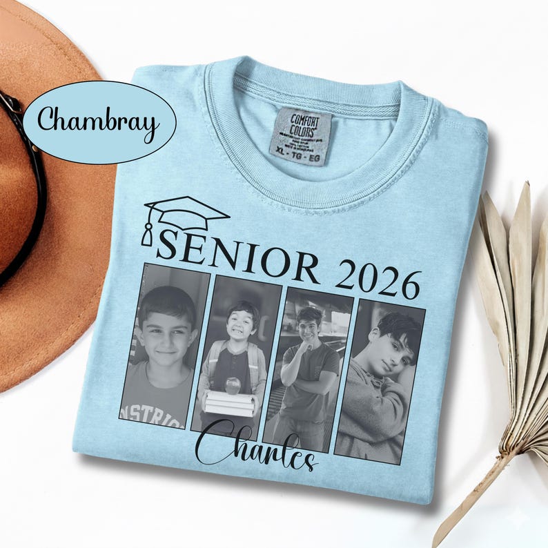 Puede incluir: Camiseta azul claro con cuello redondo, con un gr&aacute;fico de birrete y el texto "SENIOR 2026". La camiseta incluye cuatro paneles de fotos en blanco y negro y el nombre "Charles" en cursiva. La camiseta est&aacute; etiquetada como "Comfort Colors".