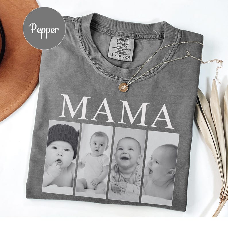 May include: A pepper-colored short-sleeve t-shirt featuring the word MAMA in white capital letters above a horizontal collage of four black and white photographs of infants. The shirt has a crew neckline and a Comfort Colors brand label inside.