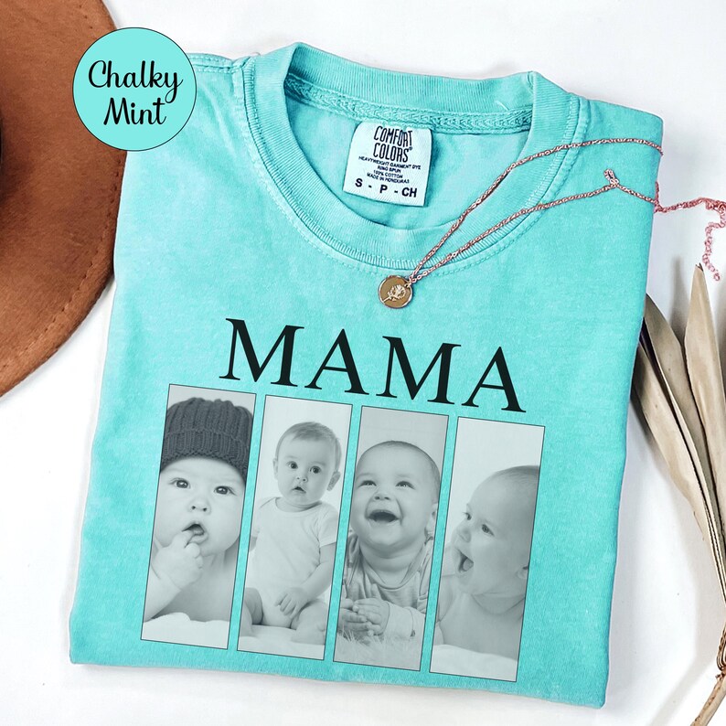 May include: A chalky mint green t-shirt featuring the word MAMA in black capital letters above four vertical rectangular photo frames containing black and white portraits of infants. The shirt has a Comfort Colors label at the inner neckline.