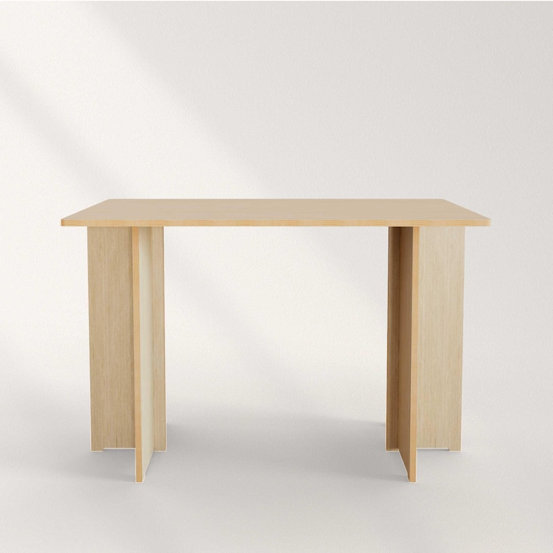 May include: A light-colored wooden table with a rectangular top and four vertical supports. The supports are made of the same light-colored wood and are positioned at each corner of the table. The table is approximately 30 inches long.