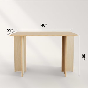 May include: A light-colored wooden table with a rectangular top and two supporting legs. The table is 46 inches long, 23 inches wide, and 30 inches high.