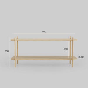 May include: A light-colored wooden shelf with two levels. The shelf is 46 inches long, 20 inches high, and 15.5 inches deep. The top shelf is 13 inches high. The design is minimalist and modern.