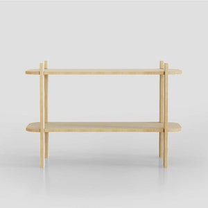 May include: A light-colored, two-tiered wooden shelf with rounded edges. The shelf has a minimalist design, with vertical supports connecting the shelves. The wood has a natural finish, and the shelf is set against a white background.