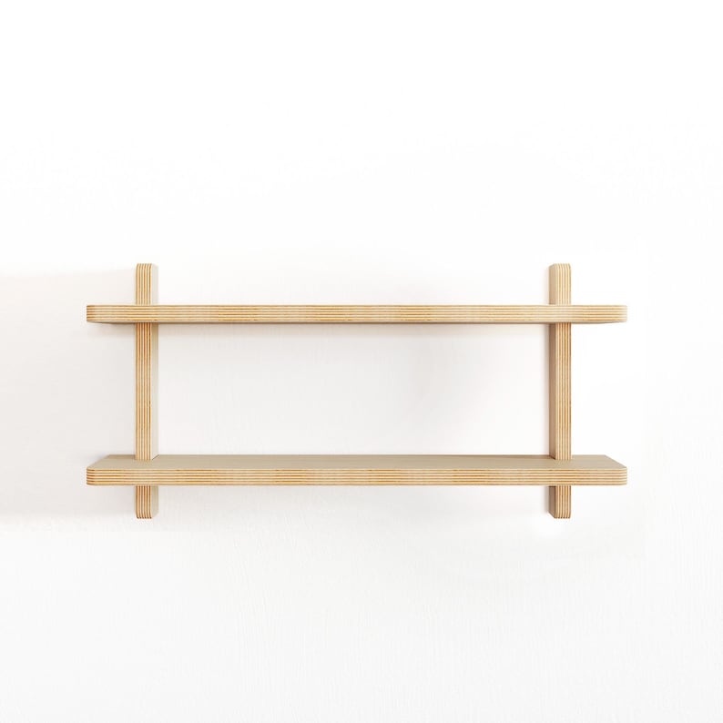May include: A two-tiered wooden shelf unit with a natural finish. The shelf is mounted to a white wall.