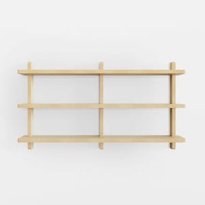 May include: A wooden wall shelf with three shelves. The shelf is made of light brown wood and has a simple, modern design.
