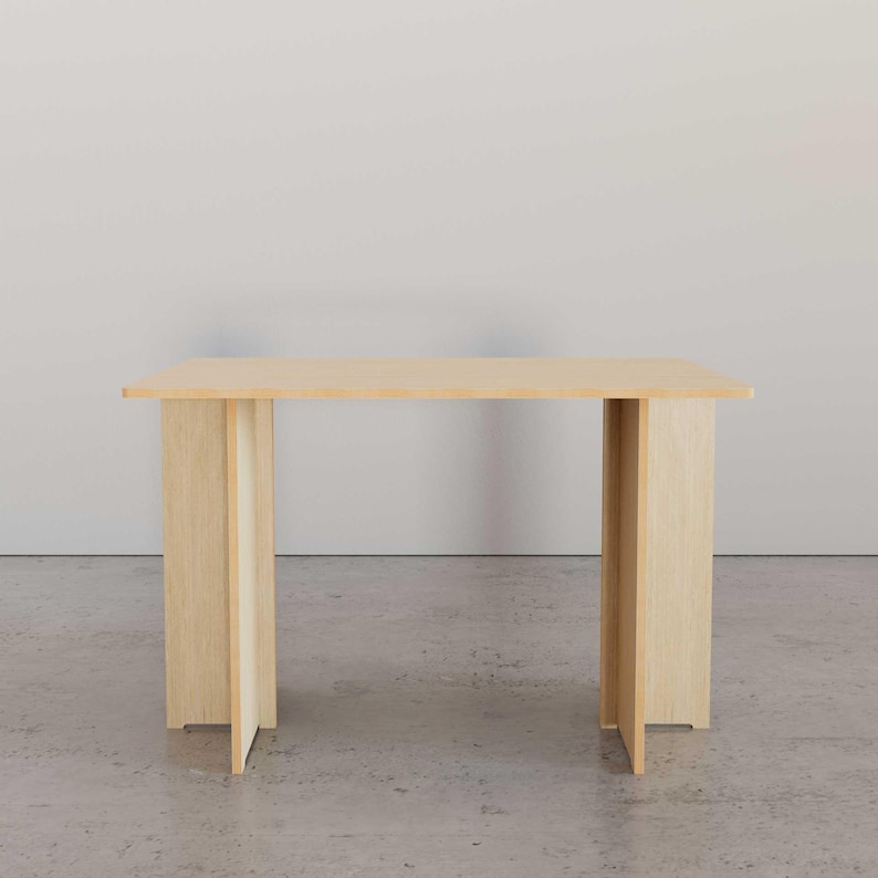 May include: A light-colored wooden table with a rectangular top and four legs. The legs are made of vertical planks that extend to the floor. The table is approximately 48 inches long and 24 inches wide.