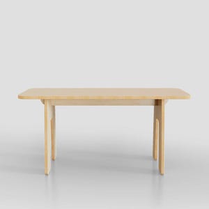 Puede incluir: Una mesa de madera clara con una tapa rectangular y un dise&ntilde;o simple y moderno. La mesa tiene cuatro patas que est&aacute;n conectadas a la tapa por una sola pieza de madera.