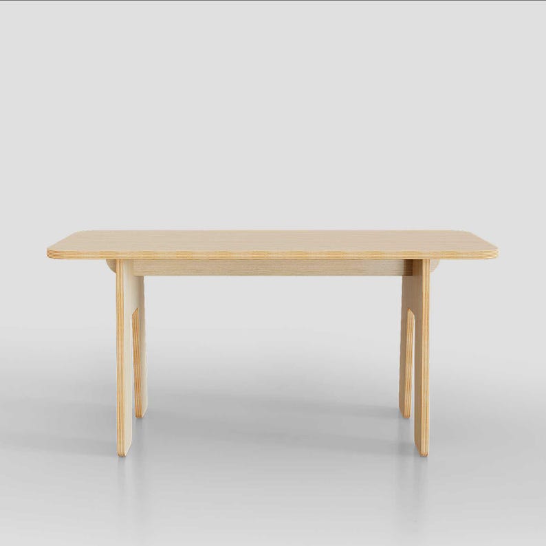 Puede incluir: Una mesa de madera clara con una tapa rectangular y un dise&ntilde;o simple y moderno. La mesa tiene cuatro patas que est&aacute;n conectadas a la tapa por una sola pieza de madera.