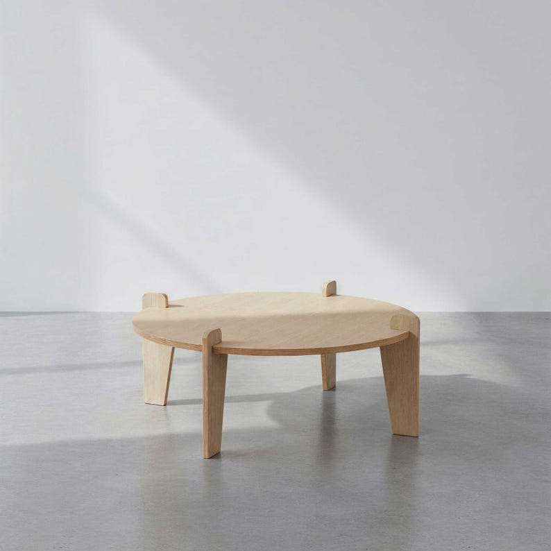 May include: A light-colored, round wooden coffee table with four legs. The table has a simple, modern design, with a smooth surface and a natural wood grain. The table is approximately 18 inches in height and 36 inches in diameter.