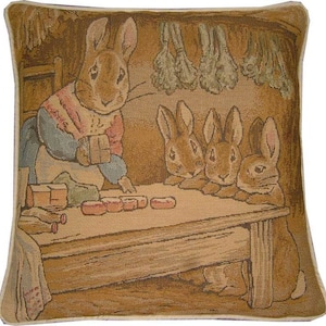 Pode incluir: Uma almofada de tapeçaria com um coelho castanho com um suéter vermelho e branco, segurando uma caixa. Outros três coelhos castanhos estão sentados em uma mesa com uma tampa de madeira. O fundo é de cor bege com vegetais verdes pendurados no teto.