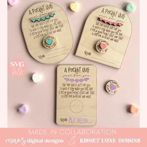 Pode incluir: Tr&ecirc;s etiquetas de madeira com o texto "A Pocket Hug Just For You" e um pequeno c&iacute;rculo recortado para um amuleto. Os amuletos s&atilde;o pequenos c&iacute;rculos de madeira com o texto "A Warm Hug From Me To You" em diferentes cores. As etiquetas est&atilde;o sobre um fundo rosa com cora&ccedil;&otilde;es de caramelo.