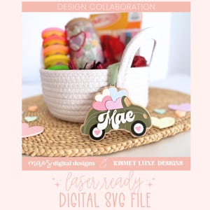 May include: A green car with pink hearts on top and the word "Mae" on the side. The car is made of wood and is a laser-cut design. The car is sitting on a woven mat.