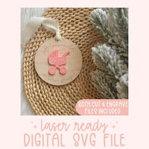 Può includere: Un ornamento rotondo in legno con il testo "For this child we have prayed" e un'illustrazione di un passeggino rosa. L'ornamento è su una superficie intrecciata. Sono inclusi file di taglio e incisione. File SVG digitale pronto per il laser.