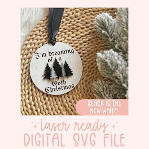 May include: White round ornament with black text that reads "I'm dreaming of a Goth Christmas". Three black trees are in the center of the ornament. The ornament is on a woven surface. The text "Black is the new white!" is in a pink rectangle below the ornament.