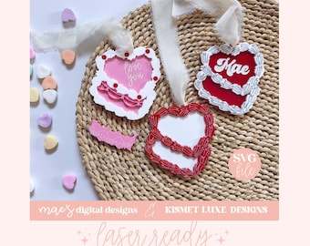 Può includere: Due file SVG a forma di cuore tagliati al laser, uno rosa con il testo "love you" e uno rosso con il testo "Mae". I cuori sono su un tappetino di paglia intrecciato con cuori di caramelle rosa e bianchi sparsi intorno.
