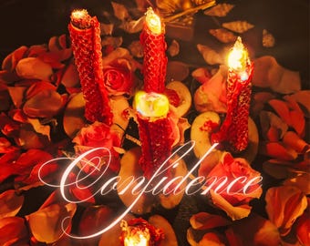 May include: A spiritual arrangement featuring three lit red candles surrounded by rose petals and slices of fruit. A golden statue is in the background. The word "Confidence" is written in a cursive font across the image.