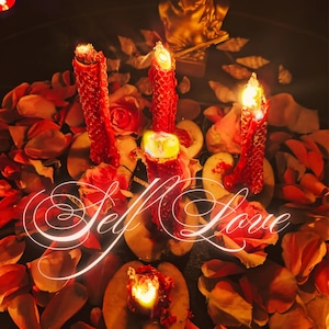 May include: A candlelit display with the words "Self Love" in elegant script. Red pillar candles are surrounded by rose petals and slices of fruit. A golden statue is in the background, creating a warm, inviting atmosphere.