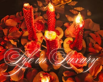 May include: A close-up of a romantic arrangement with three lit red candles, rose petals, and fruit slices. A golden statue is in the background. The words "Life in Luxury" are written in a cursive font across the image.