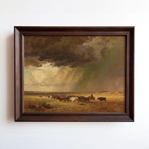 May include: A framed landscape painting depicts a cattle drive under a stormy sky. The artwork features a dark brown wooden frame. The scene shows cattle and cowboys on a plain, with a dramatic sky overhead, and a rain shower in the distance.