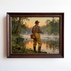 May include: Framed painting of a fisherman standing in a river at dawn. The fisherman wears a plaid shirt, waders, and a hat, holding a fishing rod. The scene is set in a forest with a misty river and a colorful sunrise.
