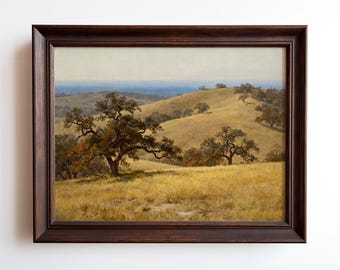 May include: A framed landscape painting depicting rolling hills with scattered trees under a pale blue sky. The artwork features a palette of golden yellows, greens, and browns, with a dark brown wooden frame.