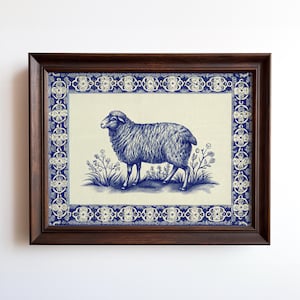 May include: A framed print featuring a blue and white illustration of a sheep standing in a field of flowers. The artwork is framed in a dark brown wooden frame with a decorative blue border. The sheep is the focal point.