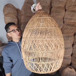 May include: A large, round, woven wicker lampshade with a natural brown color. The lampshade is made of thin, interwoven strips of wicker, creating a delicate and airy design.