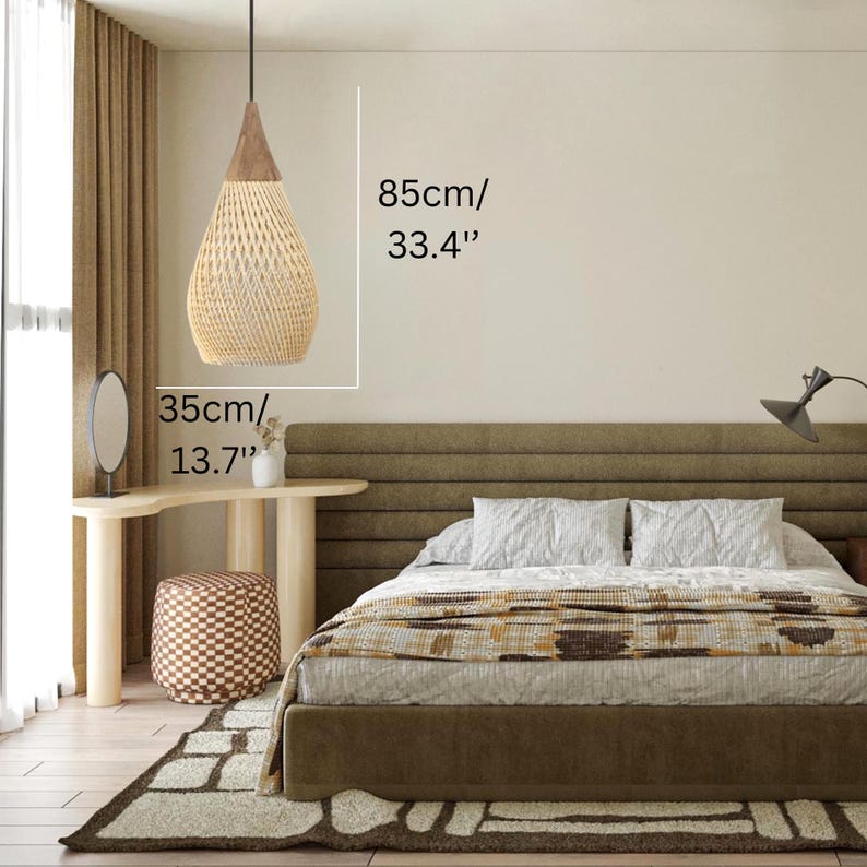 K&ouml;nnte beinhalten: Gewebte Pendelleuchte in Tropfenform, 85 cm hoch und 35 cm im Durchmesser. Die Leuchte hat eine nat&uuml;rliche beige Farbe mit einem braunen Holzaufsatz und h&auml;ngt an einem schwarzen Kabel. Sie befindet sich &uuml;ber einem Bett.