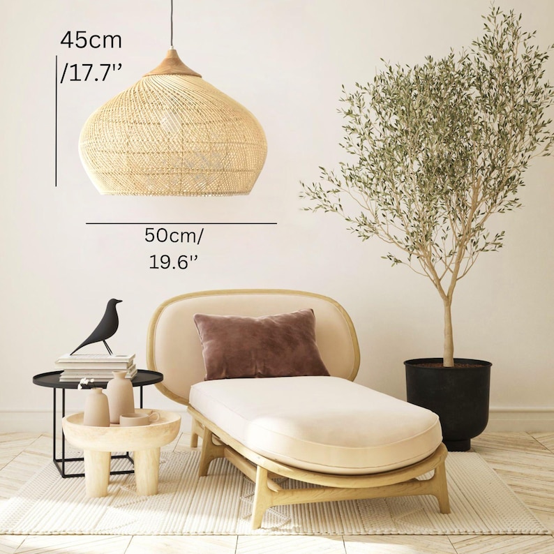 K&ouml;nnte beinhalten: Eine gewebte Pendelleuchte, 45 cm hoch und 50 cm im Durchmesser, h&auml;ngt &uuml;ber einer Chaiselongue. Die Leuchte hat eine nat&uuml;rliche, beige Farbe. Ein kleiner Beistelltisch und ein Olivenbaum im Topf vervollst&auml;ndigen die Szene.
