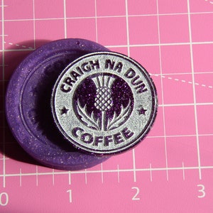May include: A silver-colored round stamp with the text "CRAIGH NA DUN COFFEE" and a purple glitter thistle design.