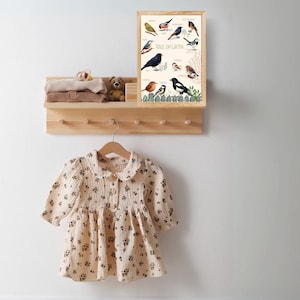 Könnte beinhalten: Eine gerahmte Illustration verschiedener Vögel mit ihren Namen in Deutsch. Die Illustration ist mit "Vögel im Garten" betitelt und zeigt eine Vielzahl von Vögeln, darunter einen Rotkehlchen, eine Blaumeise und eine Elster. Die Illustration ist auf weißem Hintergrund gedruckt und in einem einfachen Holzrahmen gerahmt.