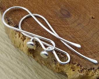 May include: A pair of silver earring hooks with small round balls at the end.
