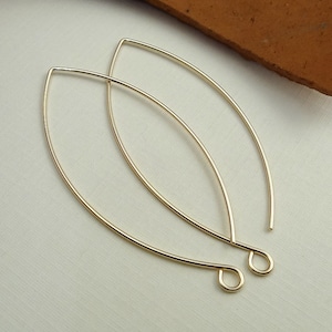 May include: Two gold-toned, wire, oval-shaped earring hoops. The hoops are open at the top and have a small loop at the bottom for attaching to an earring hook.