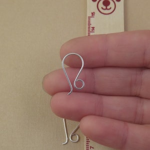 May include: Silver earring hook with a loop at the top and a small loop at the bottom. The hook is about 1 inch long.