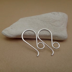 May include: A pair of silver earring hooks with a simple, elegant design. The hooks are made of metal and have a smooth, polished finish.