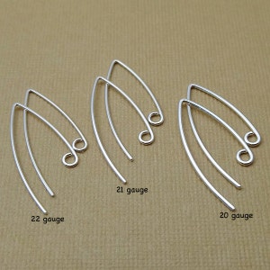 May include: Three pairs of silver earring hooks in different gauges. The hooks are made of thin, flexible wire and have a small loop at the end. The gauges are labeled 22 gauge, 21 gauge, and 20 gauge.
